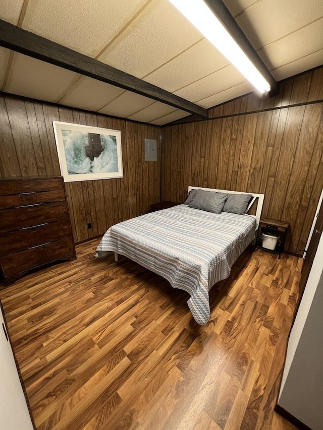 bedroom with wood walls, wood finished floors, and beam ceiling