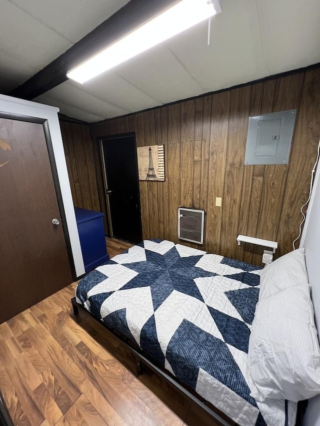 bedroom featuring wood finished floors, electric panel, and wooden walls