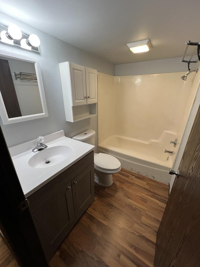 bathroom with toilet, shower / bathing tub combination, wood finished floors, and vanity