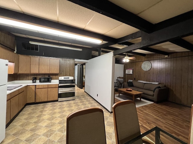 kitchen with beam ceiling, light countertops, open floor plan, wood walls, and double oven range