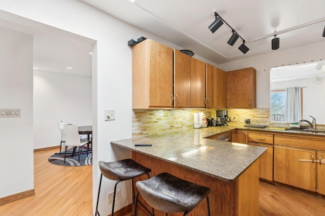 kitchen with light wood-style floors, backsplash, and a peninsula