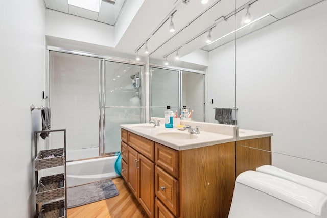 bathroom with double vanity, wood finished floors, a sink, and toilet