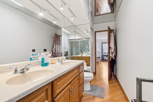 bathroom featuring double vanity, a sink, toilet, and a shower stall