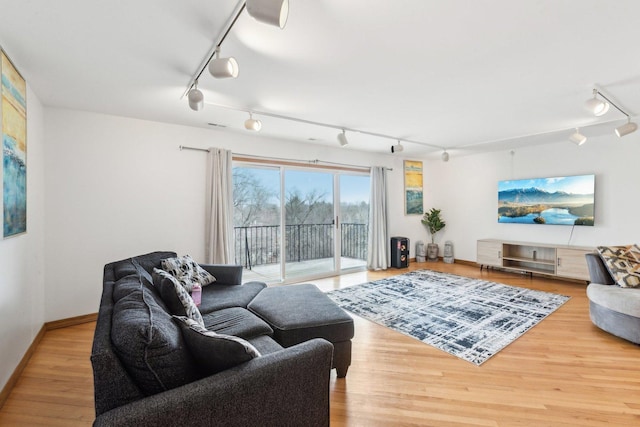 living area featuring track lighting, baseboards, and wood finished floors