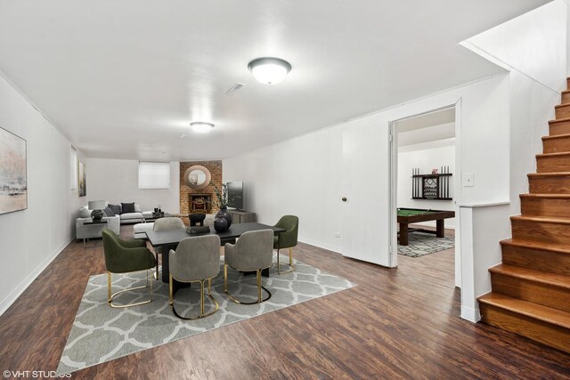 dining space featuring visible vents, dark wood finished floors, pool table, stairs, and a brick fireplace