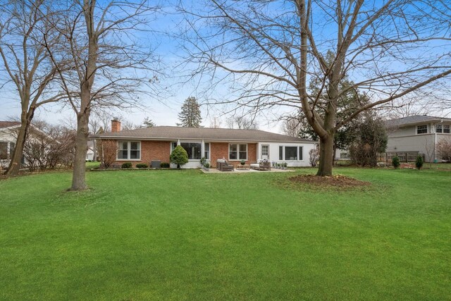 single story home featuring brick siding, a patio, a chimney, and a front lawn