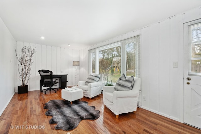 living area featuring a decorative wall, wood finished floors, and a healthy amount of sunlight