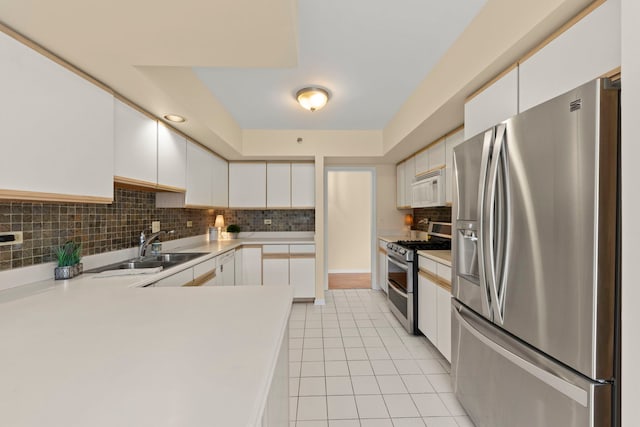 kitchen with appliances with stainless steel finishes, a sink, light tile patterned floors, tasteful backsplash, and light countertops