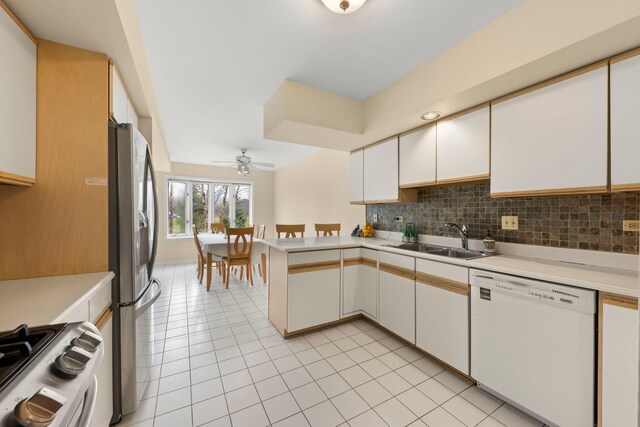 kitchen featuring stainless steel appliances, a sink, light countertops, and light tile patterned flooring