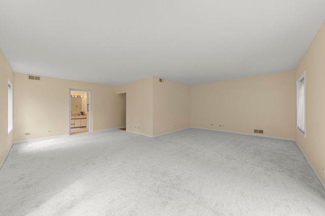 unfurnished room featuring light colored carpet and baseboards