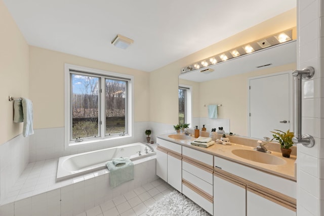full bath with healthy amount of natural light, a bath, double vanity, and tile patterned flooring
