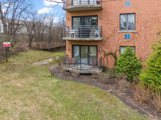 view of green lawn featuring a balcony