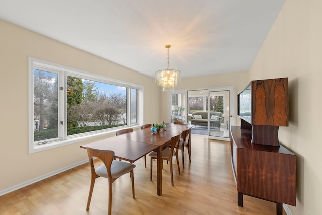dining space featuring light wood-style flooring, a chandelier, and baseboards
