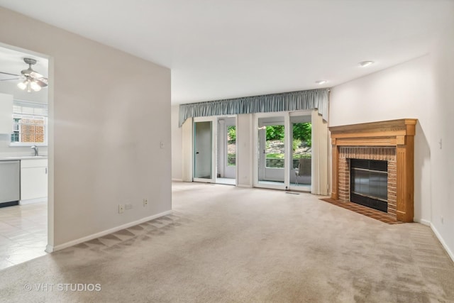 unfurnished living room with light carpet, a brick fireplace, a sink, and baseboards