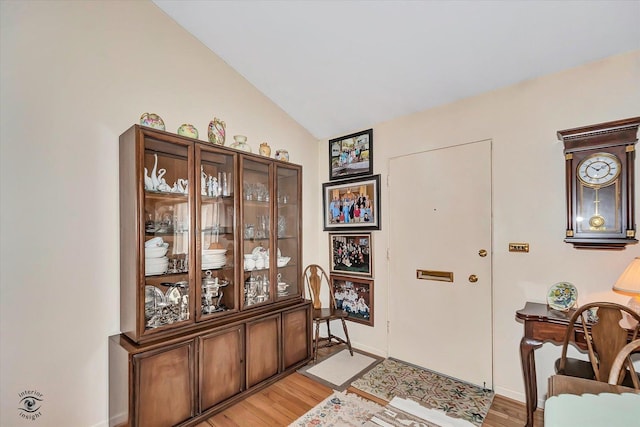 foyer entrance featuring vaulted ceiling, light wood-style flooring, and baseboards