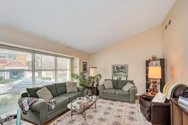 living area featuring visible vents, vaulted ceiling, and light wood finished floors