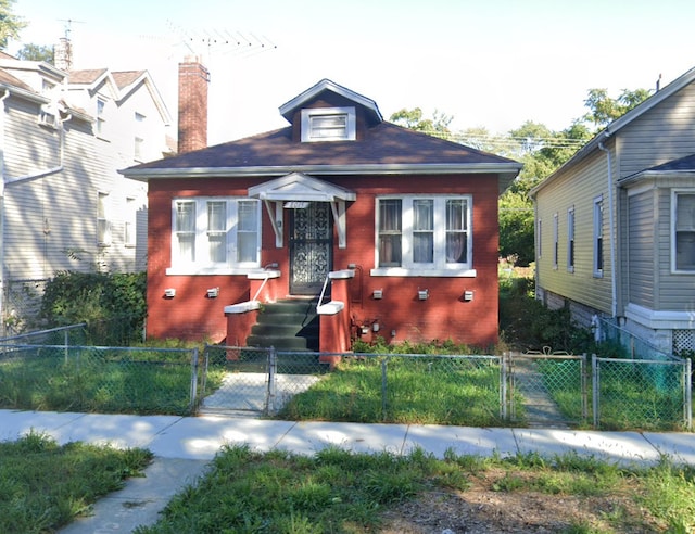 view of front of property featuring brick siding, a fenced front yard, and a gate