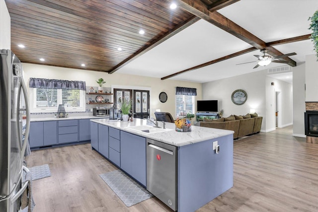 kitchen with visible vents, a center island with sink, a sink, stainless steel appliances, and light wood-style floors