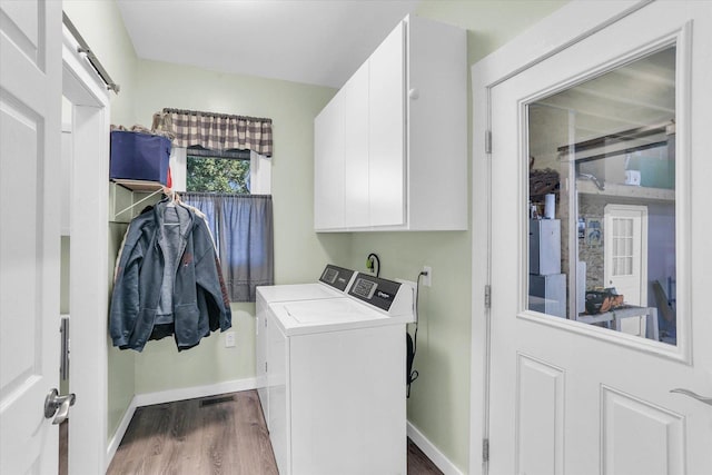 laundry room featuring dark wood-type flooring, cabinet space, baseboards, and washing machine and clothes dryer