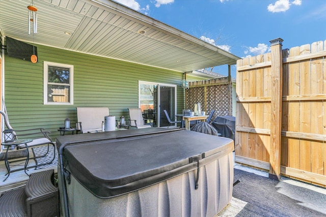 view of patio with a hot tub and fence