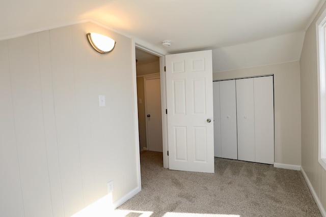 unfurnished bedroom featuring light carpet, vaulted ceiling, and a closet