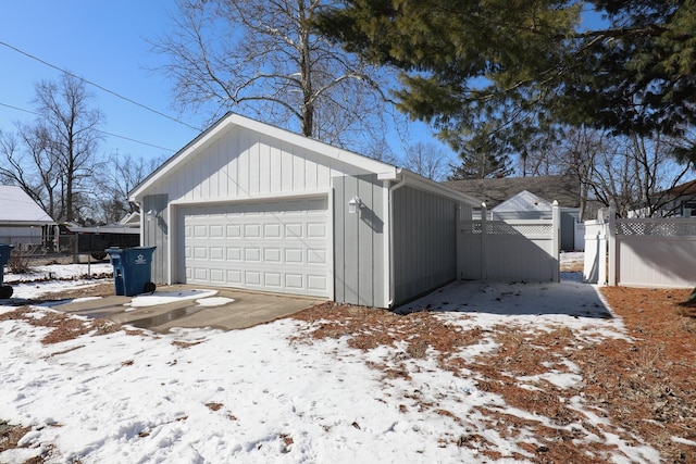 snow covered garage with a garage and fence