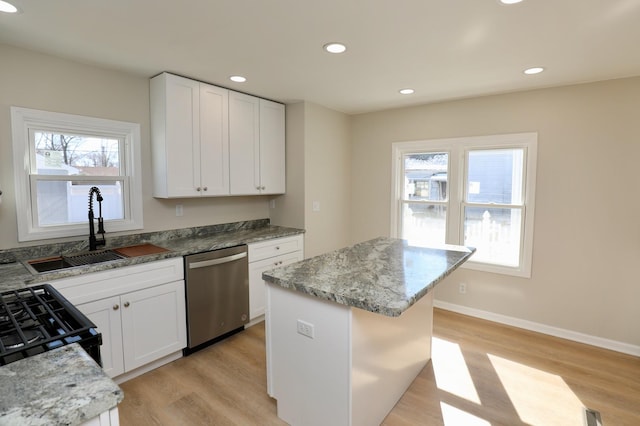 kitchen featuring a sink, a kitchen island, white cabinetry, range with gas stovetop, and dishwasher