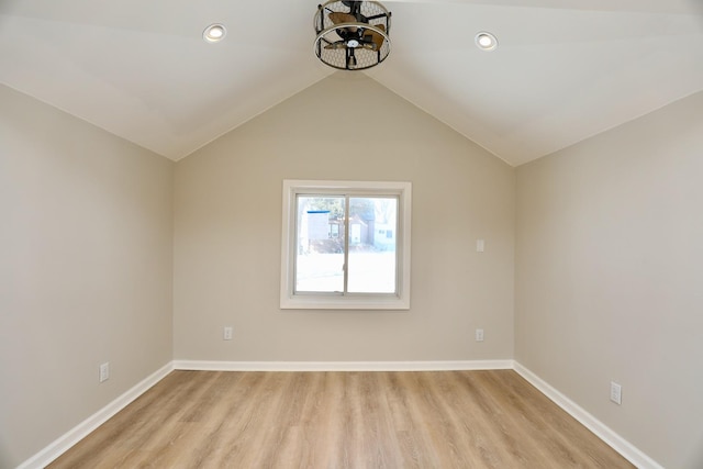 spare room with light wood finished floors, baseboards, and vaulted ceiling