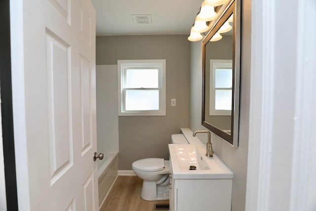 full bath with toilet, wood finished floors, visible vents, vanity, and a bathtub