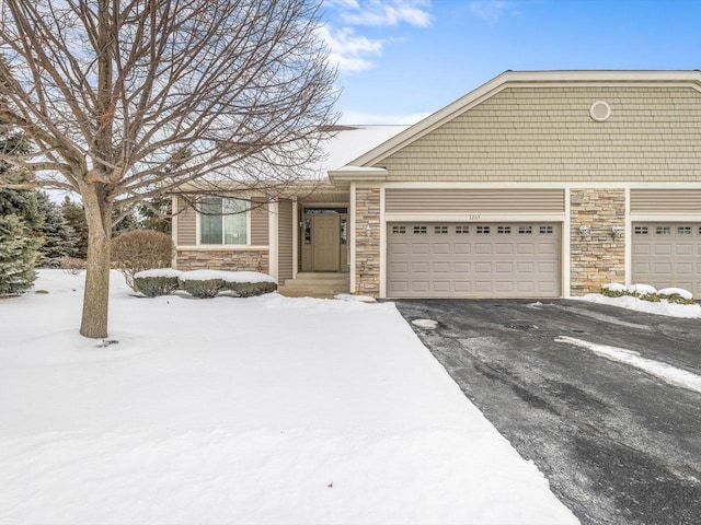 view of front of house with aphalt driveway, stone siding, and an attached garage