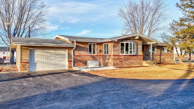 ranch-style home featuring a garage, driveway, and brick siding