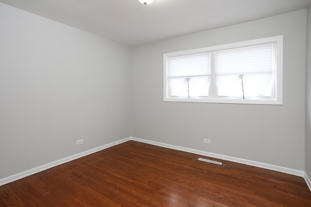 unfurnished room with visible vents, baseboards, and wood finished floors