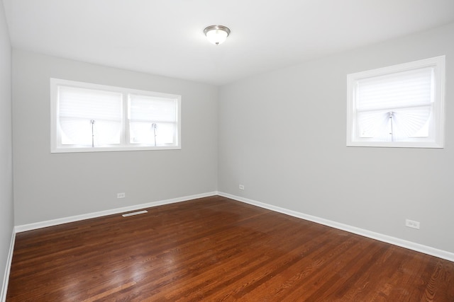 spare room featuring visible vents, dark wood finished floors, and baseboards