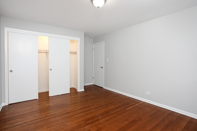 unfurnished bedroom featuring a closet, dark wood-style flooring, and baseboards