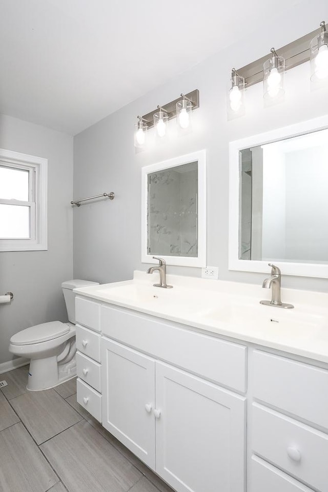 bathroom with toilet, double vanity, and a sink