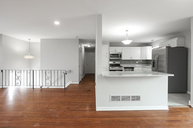 kitchen with stainless steel appliances, wood finished floors, visible vents, white cabinetry, and decorative backsplash