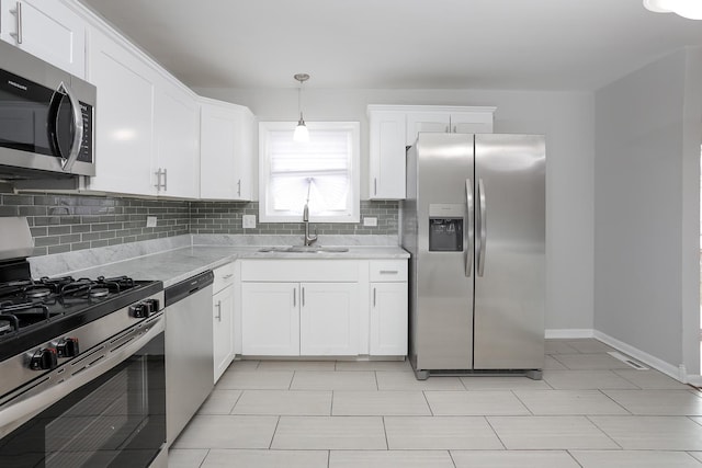 kitchen with light stone counters, a sink, white cabinets, appliances with stainless steel finishes, and backsplash