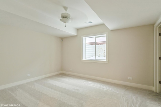 spare room featuring light carpet, ceiling fan, visible vents, and baseboards