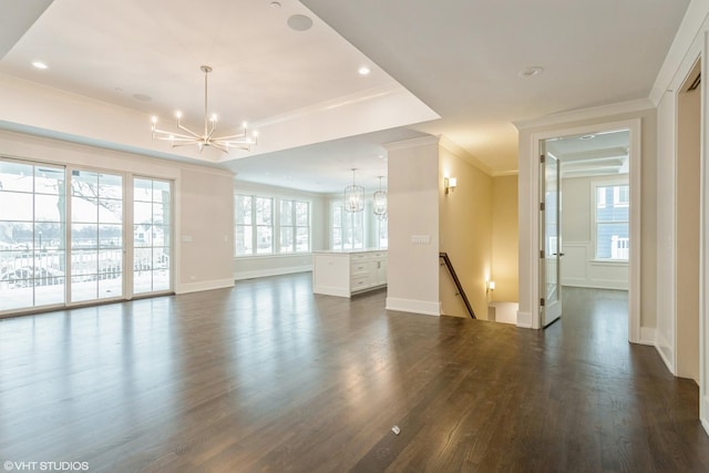 unfurnished room with an inviting chandelier, a tray ceiling, ornamental molding, and dark wood-type flooring