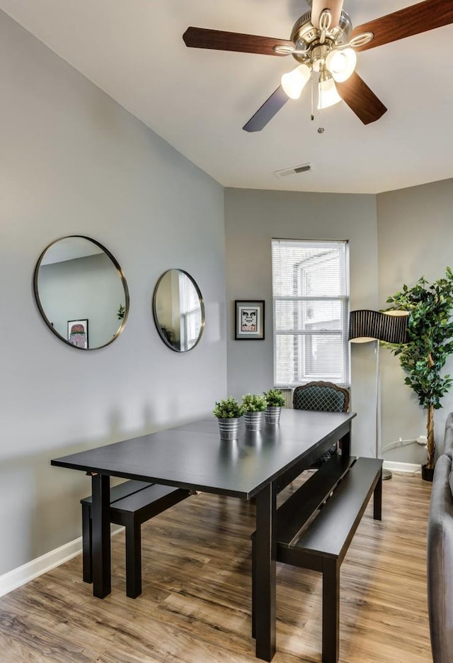 dining space with wood finished floors, visible vents, and baseboards