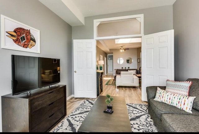 living room with ceiling fan, baseboards, and light wood-style floors