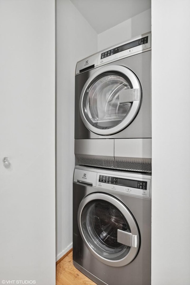 washroom featuring stacked washer and dryer, laundry area, and light wood-style floors