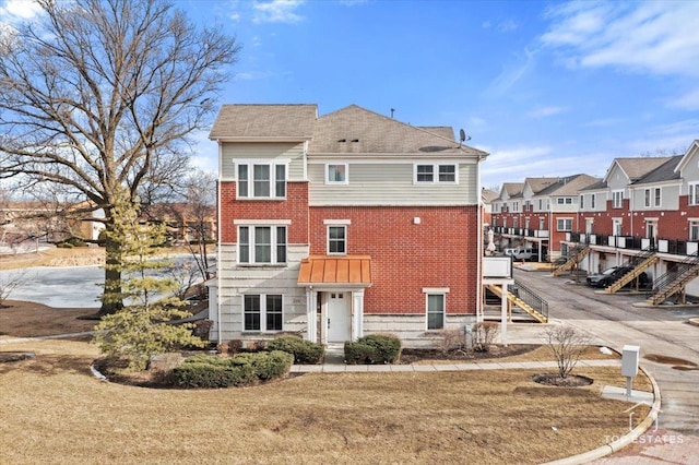 exterior space with brick siding, a lawn, a residential view, and stairway