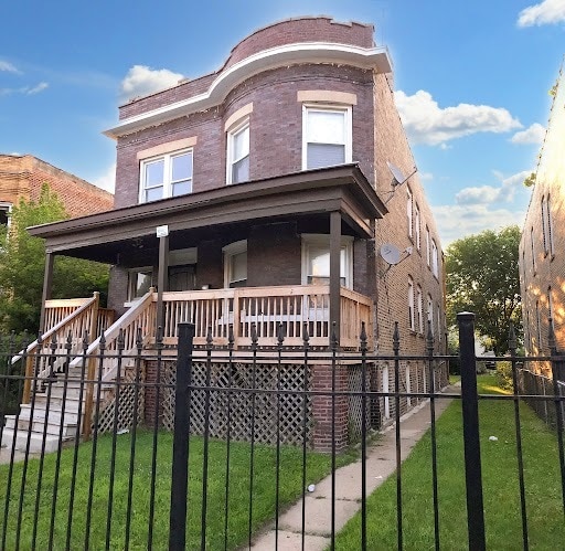 view of front of house with covered porch, a front lawn, fence, and brick siding