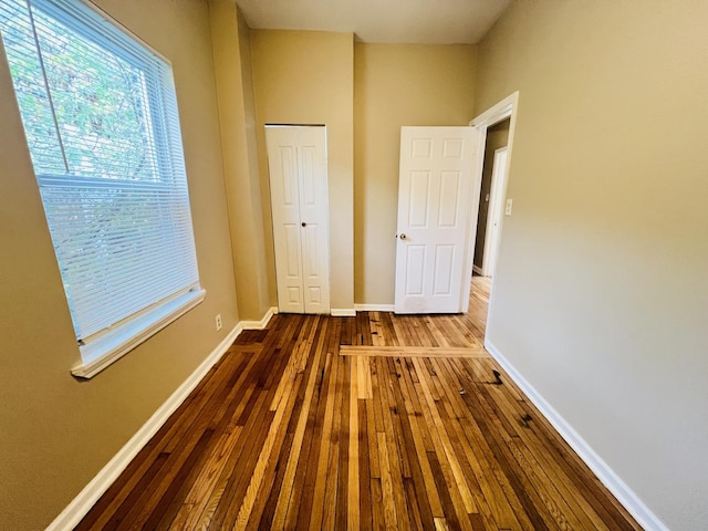 unfurnished bedroom featuring a closet, wood finished floors, and baseboards