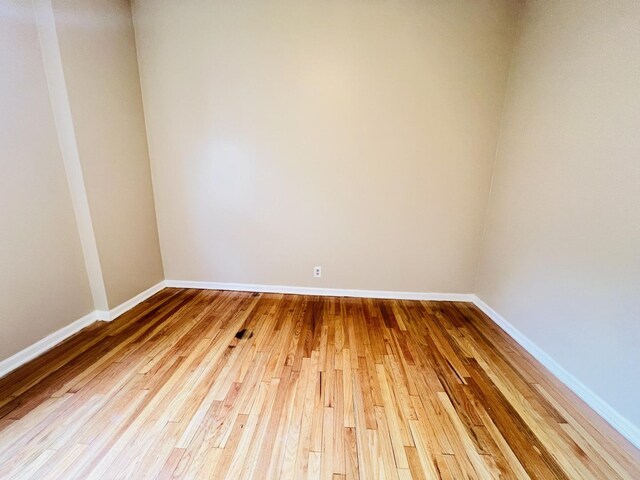 spare room featuring baseboards and wood finished floors