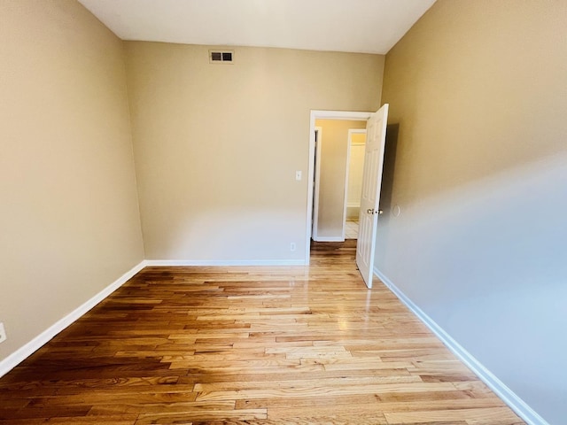 empty room with light wood-type flooring, visible vents, and baseboards