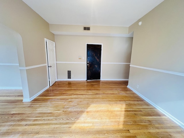 unfurnished room featuring visible vents, light wood-style flooring, and baseboards