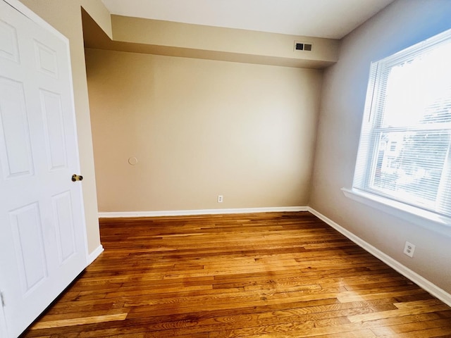 unfurnished room featuring wood finished floors, visible vents, and baseboards