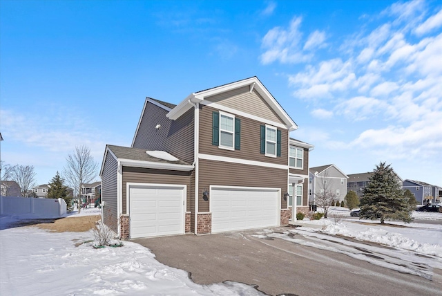 traditional home with a garage, a residential view, fence, and aphalt driveway